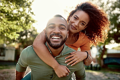 Buy stock photo Portrait a young man giving his girlfriend a piggyback ride outdoors