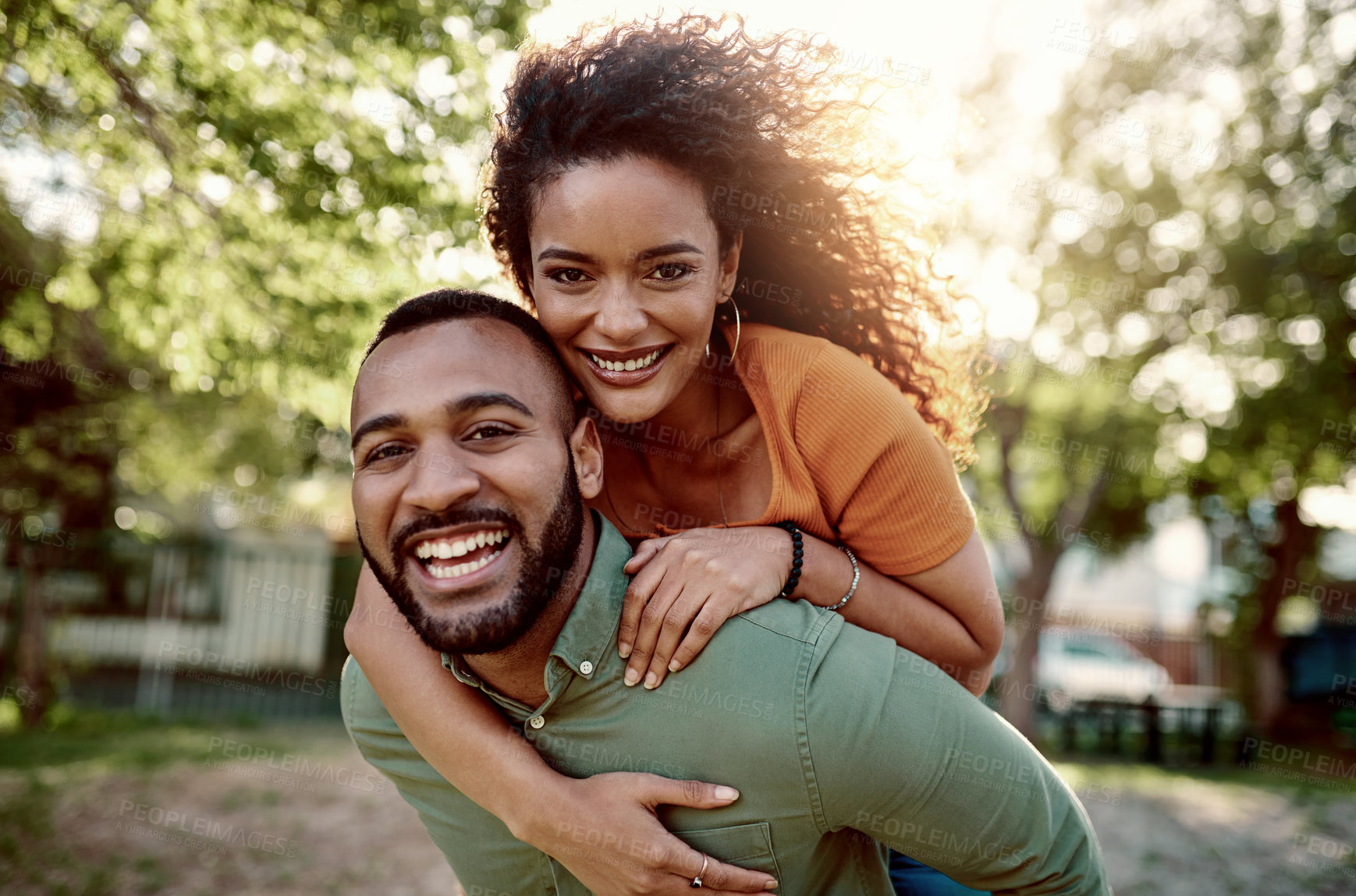 Buy stock photo Portrait a young man giving his girlfriend a piggyback ride outdoors