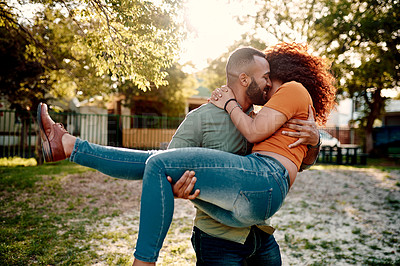 Buy stock photo Shot of a young man carrying his girlfriend outdoors