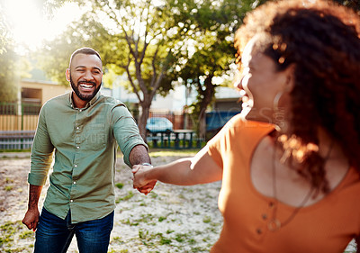 Buy stock photo Shot of a young man holding his girlfriend's hand while walking together in a park