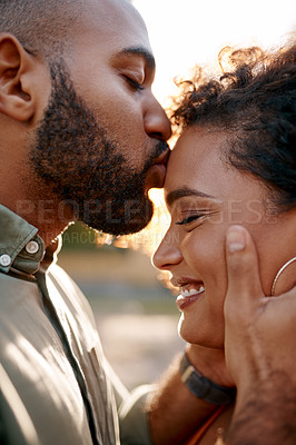 Buy stock photo Shot of a young man giving his girlfriend a kiss on the forehead outdoors
