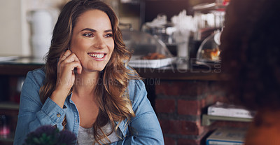 Buy stock photo Shot of a young woman chatting to her friend in a cafe