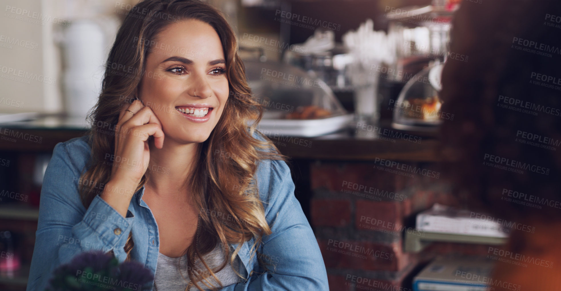 Buy stock photo Shot of a young woman chatting to her friend in a cafe