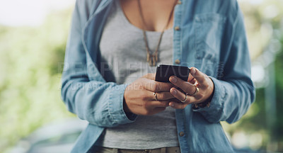 Buy stock photo Closeup shot of an unrecognisable woman using a cellphone while out in the city