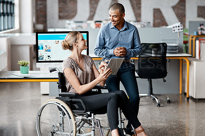 Buy stock photo Shot of two businesspeople using a digital tablet together in an office