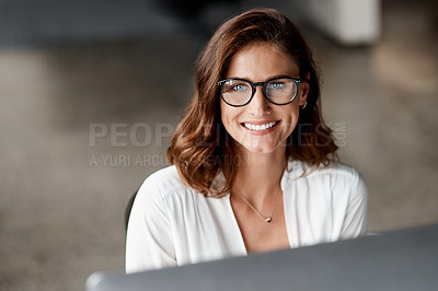 Buy stock photo Shot of an attractive young businesswoman sitting alone in the office and using her computer