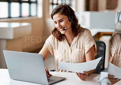 Buy stock photo Shot of a young businesswoman wearing a headset while working on a laptop in an office