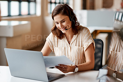 Buy stock photo Shot of a young businesswoman wearing a headset while working on a laptop in an office
