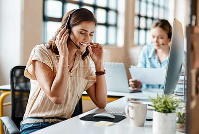 Buy stock photo Shot of a young businesswoman wearing a headset while working on a computer in an office