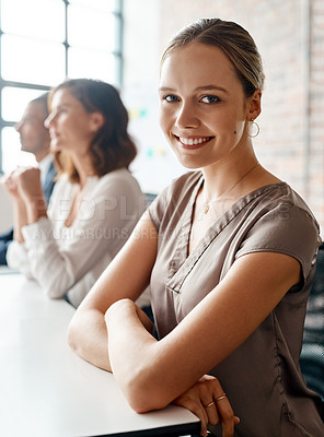 Buy stock photo Portrait of a young businesswoman sitting in an office with her colleagues in the background