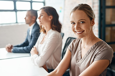 Buy stock photo Portrait of a young businesswoman sitting in an office with her colleagues in the background