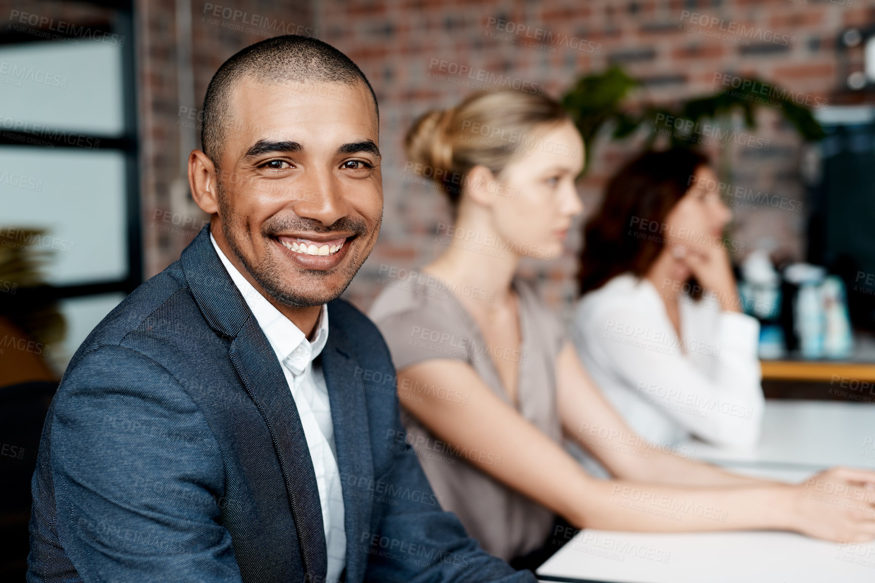 Buy stock photo Portrait of a young businessman sitting in an office with his colleagues in the background