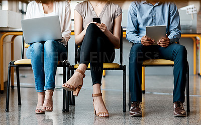 Buy stock photo Closeup shot of a group of unrecognisable businesspeople using digital devices while sitting in a row in an office