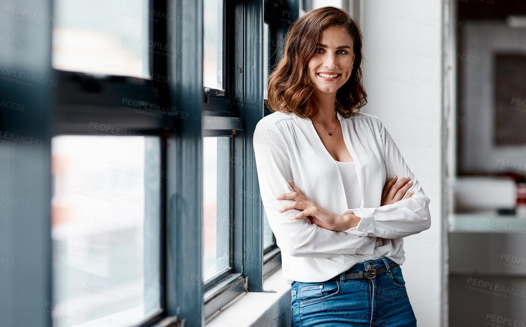 Buy stock photo Portrait of a confident young businesswoman standing at a window in an office