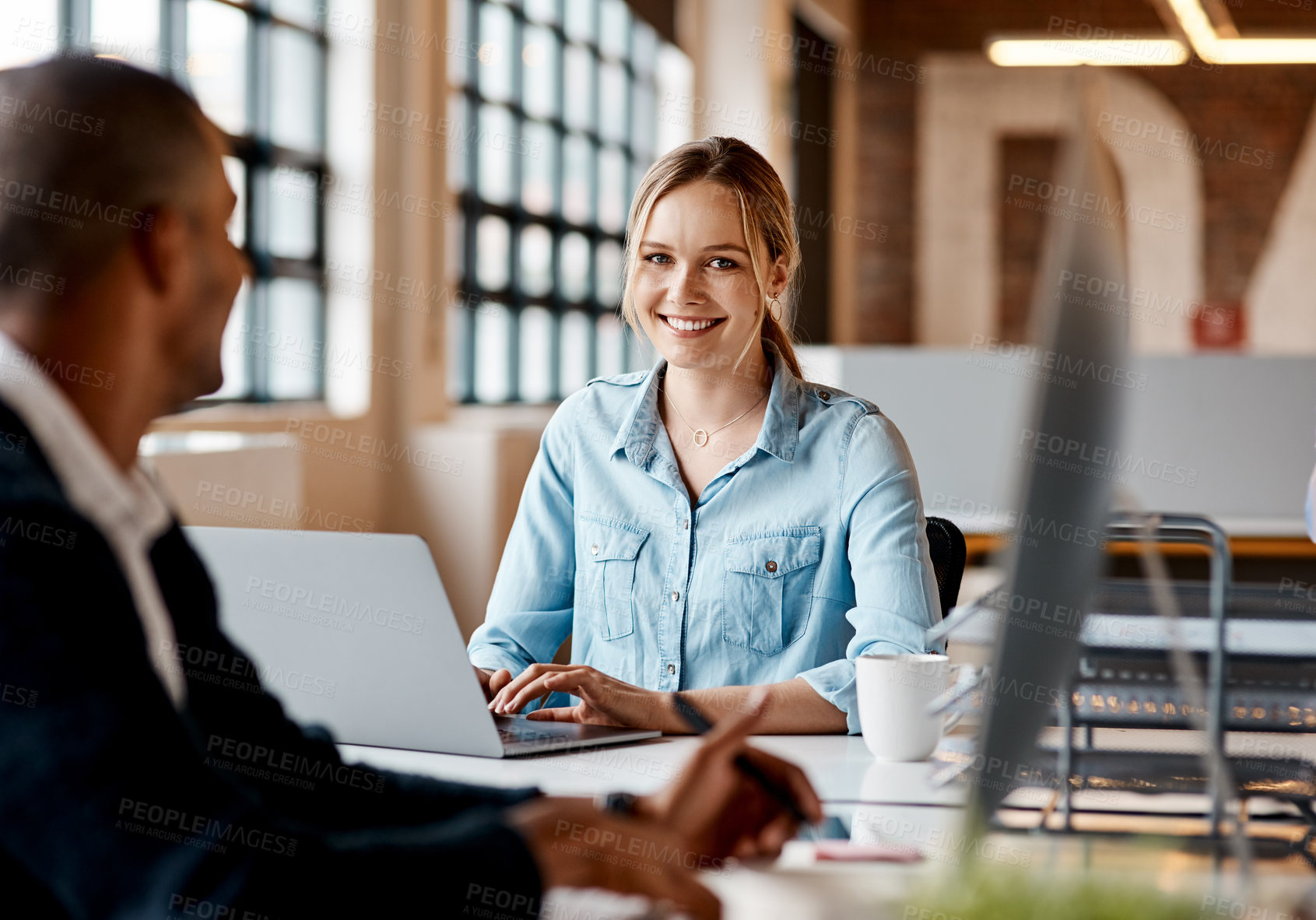 Buy stock photo Shot of a young businesswoman having a discussion with her colleague in a modern office