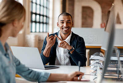 Buy stock photo Shot of a young businessman having a discussion with his colleague in a modern office