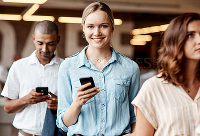 Buy stock photo Shot of a young businesswoman using a smartphone while waiting in line in a modern office