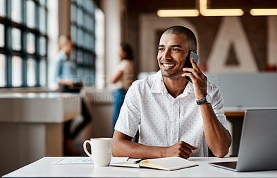 Buy stock photo Shot of a young businessman using a laptop and smartphone in a modern office