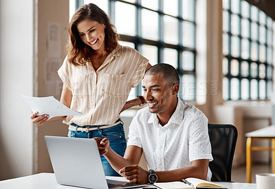 Buy stock photo Shot of a young businessman using a laptop with his colleague in a modern office