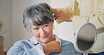 Haircare, senior mother or woman in house with mirror, grooming or family bonding in morning routine. Smile, elderly mom or daughter with tool, getting ready or hair styling assistance in retirement.
