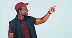 Pointing, space and delivery man in studio for shipping news, advertising and ecommerce info. Mockup, happy and African person with gesture for logistics, courier service and tips on blue background