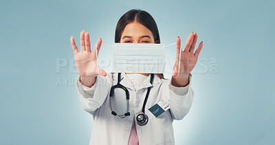 Buy stock photo Portrait, woman and doctor in studio with face mask, wink or infection control for virus prevention. Healthcare worker, playful person and medical rules for safety, PPE or protocol on blue background