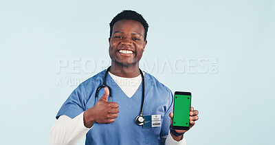Buy stock photo Nurse, phone or black man with thumbs up or green screen for advertising on a blue studio background. Male person, healthcare worker or portrait with smile, smartphone display or app on mockup space