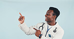 Black man, doctor and pointing in studio with smile, advertising and sign up for medical advice. Space, person and hand gesture for presentation, coming soon and healthcare service on blue background
