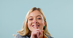 Portrait, girl and secret in studio with finger to lips, mockup space and body language with smile. Happy woman, confidential or private with gesture for quiet, silence or censor on blue background