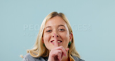 Buy stock photo Portrait, girl and secret in studio with finger to lips, mockup space and body language with smile. Happy woman, confidential or private with gesture for quiet, silence or censor on blue background