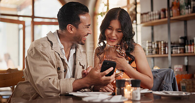 Buy stock photo Couple, laughing and bonding with phone in restaurant, love and watching funny video on social media. Happy people, online and relax with mobile in diner, date and streaming comedy with technology