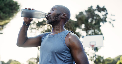 Buy stock photo Sports, man and drinking water on basketball court for exercise recovery, wellness or health on break. African person, bottle and mature athlete with electrolytes, fitness and hydration outdoor