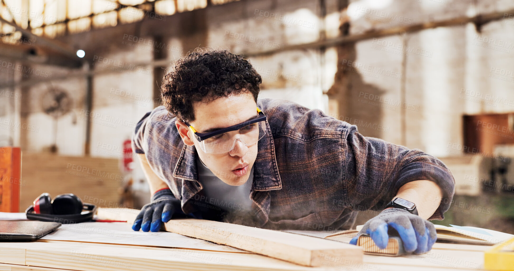 Buy stock photo Carpenter, sanding and man blow dust in workshop with wood for clean, productivity or production. Person, safety gear and warehouse with tools for custom or handmade woodworking, workbench and timber