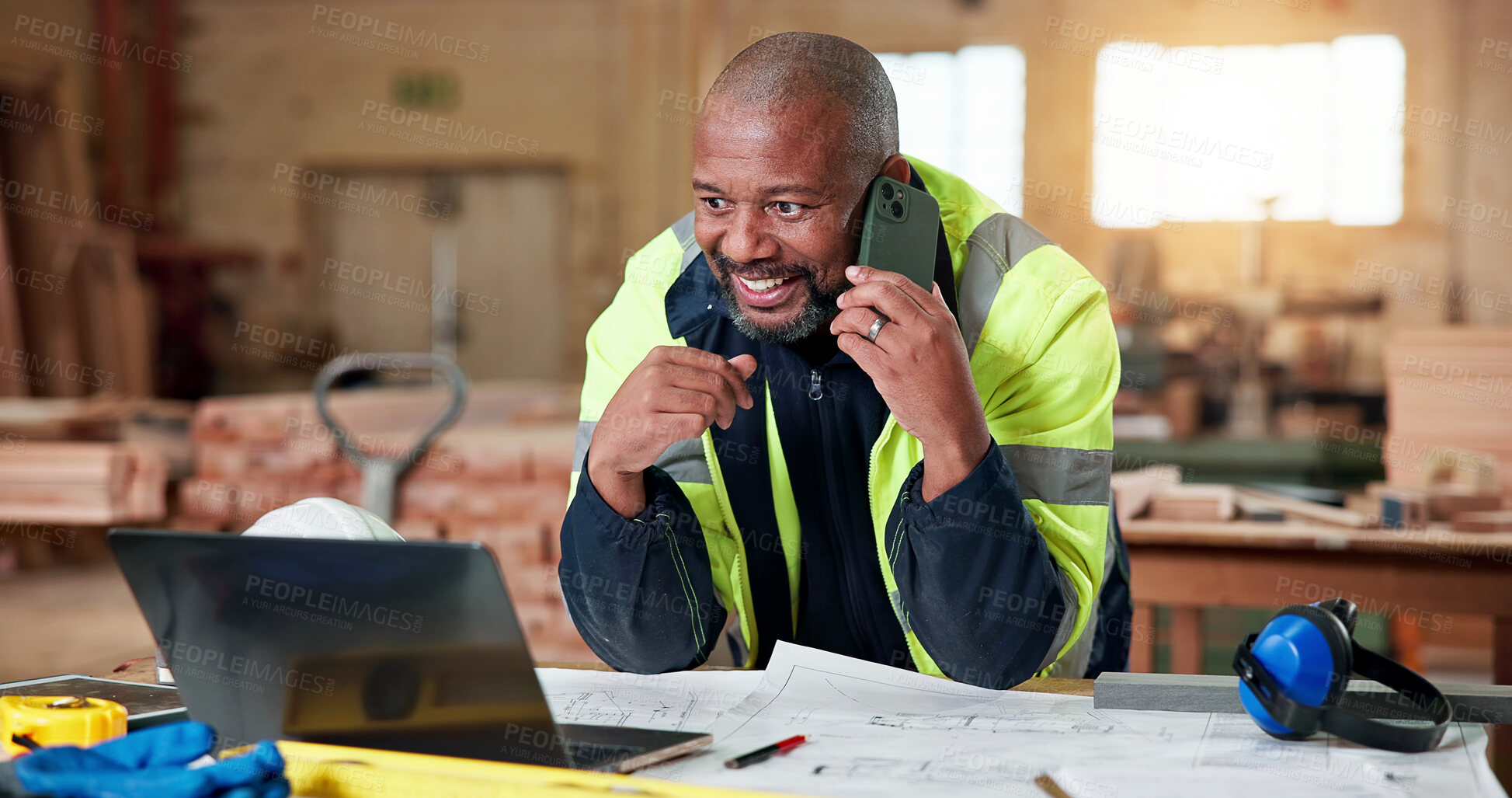 Buy stock photo Construction, phone call and smile with black man in carpentry workshop for lumber or timber supply. Computer, conversation and floor plan with mature carpenter in woodwork factory for building order