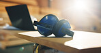 Carpentry, industry and earmuffs on desk n workshop for hearing protection or safety equipment. Woodworking, laptop and noise reduction headphones on table for timber project in empty factory.