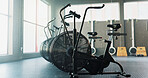 Empty, fitness and airbike in gym for cardio, wellness facility and setup for spin class with flare. Stationary bicycle, interior and equipment in training studio for cycling, development or machine
