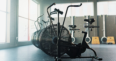 Buy stock photo Empty, fitness and airbike in gym for cardio, wellness facility and setup for spin class with flare. Stationary bicycle, interior and equipment in training studio for cycling, development or machine