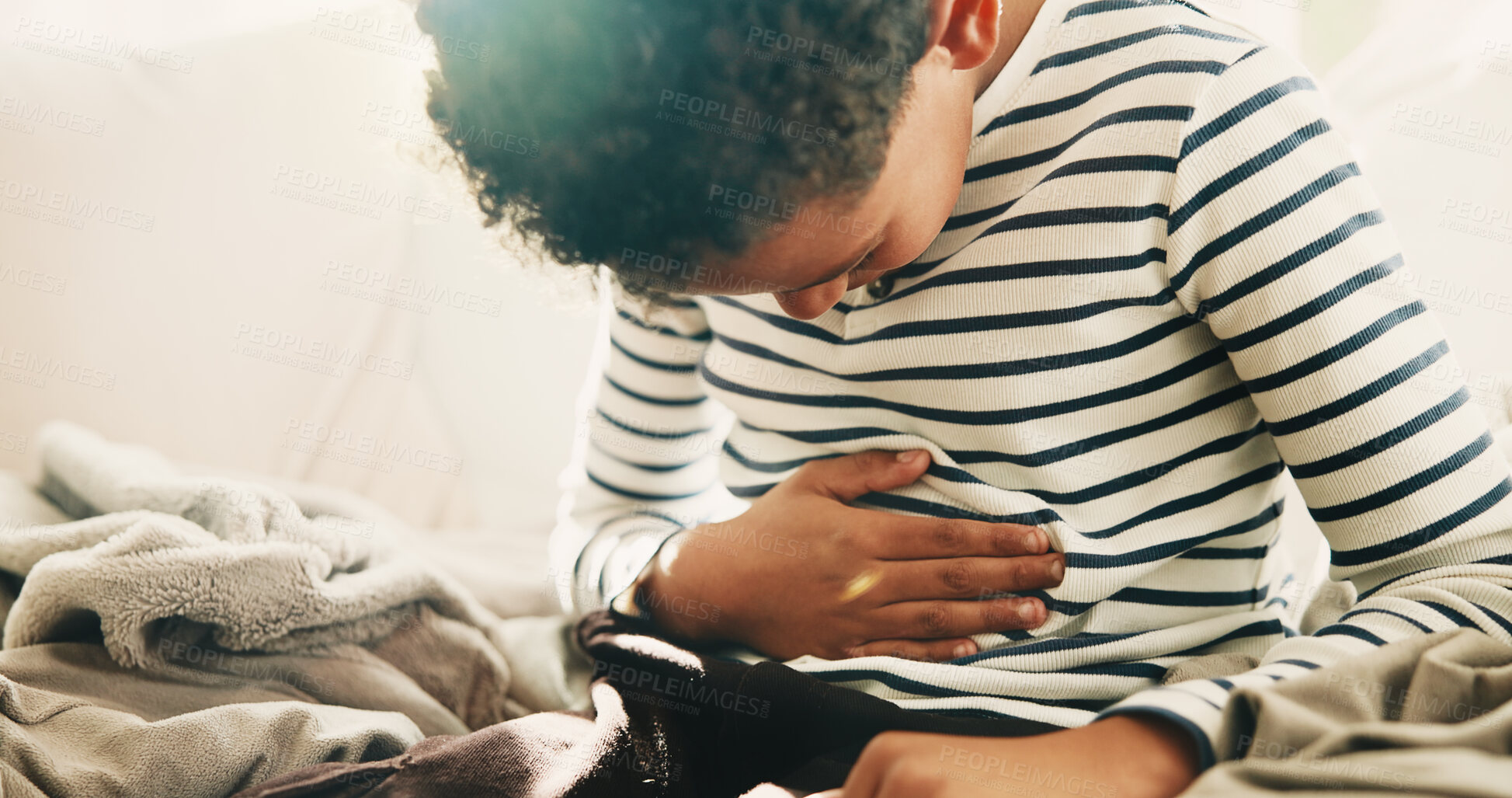 Buy stock photo Sick, child and discomfort in home with stomach ache, indigestion or constipation from medical issue. Boy, kid and abdomen pain in living room with tummy bug, bowel inflammation and bloating problem.
