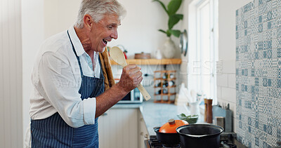 Buy stock photo Singing, cooking and senior man with spoon in kitchen at house with music, radio or album on weekend. Happy, karaoke and elderly person listening to online playlist for preparing dinner in apartment.