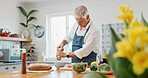 Cooking, salt and old man in kitchen with healthy nutrition, vegetables and wellness for retirement. Senior person, meal prep and seasoning food in home with lunch recipe, organic diet and spices.
