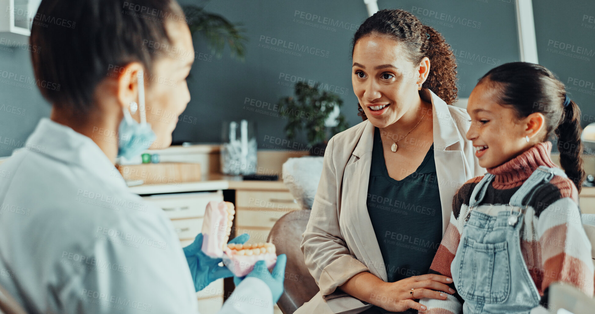 Buy stock photo Girl, dentist and mother in practice with model, teaching or instructions for dental care. Orthodontist, family and typodont in office for visual learning, teeth wellness or child patient for checkup