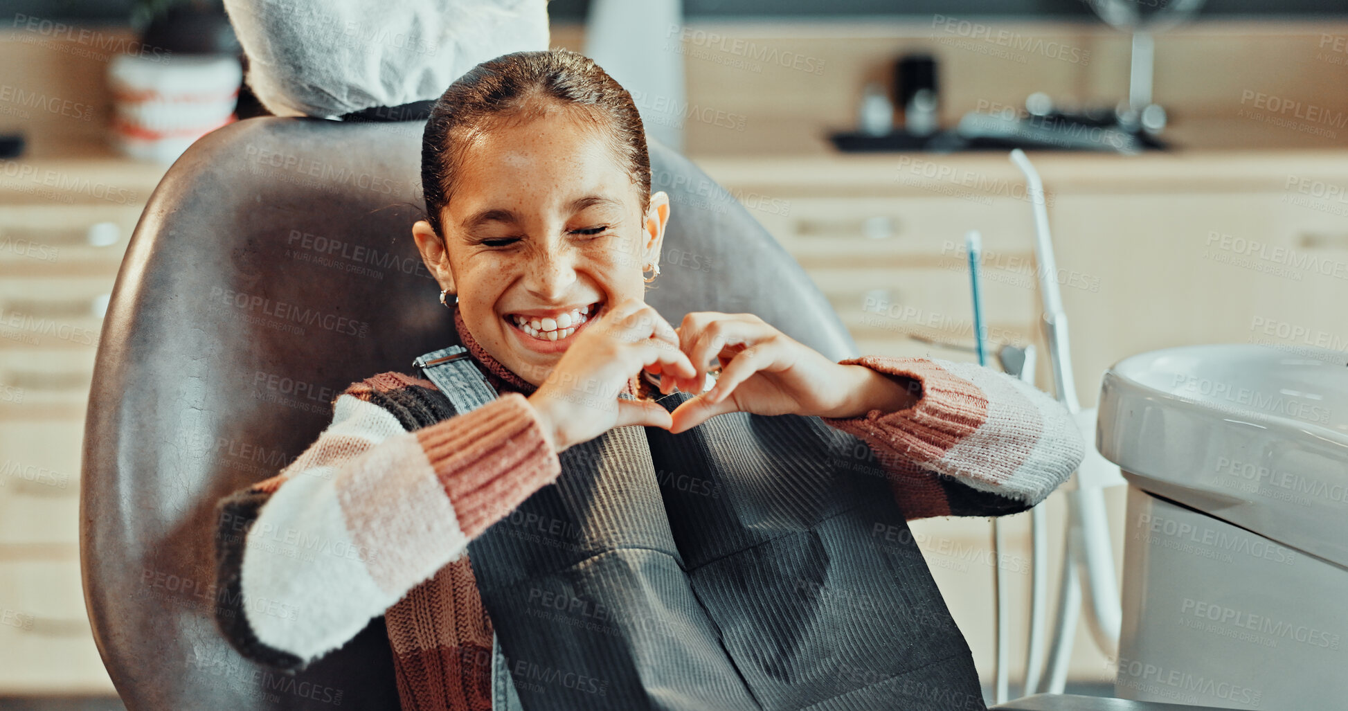 Buy stock photo Patient, dentist and happy girl with heart hands in clinic for dental appointment or healthy teeth. Child, kid or smile with like emoji, shape or satisfaction for oral hygiene, gum care or healthcare