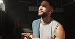 Man, thinking and phone in gym with earphones, fitness and listen to music playlist for inspiration. Person, exercise break and reflection in health club with audio tech, radio or internet connection