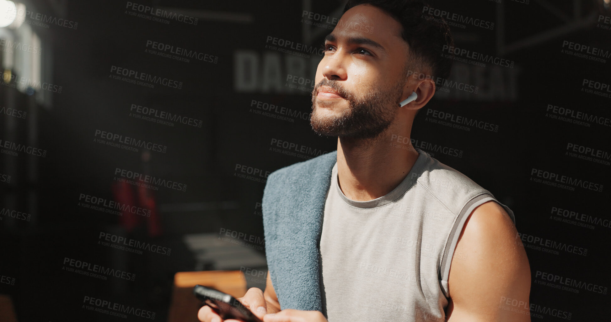 Buy stock photo Man, thinking and phone in gym with earphones, fitness and listen to music playlist for inspiration. Person, exercise break and reflection in health club with audio tech, radio or internet connection