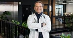 Healthcare, doctor and pride in portrait in hospital lobby, expert physician or heart specialist. Mature, man or cardiologist for medical care, confident or arms crossed with professional in medicine