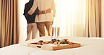 Couple, tray or hug with champagne in bedroom for honeymoon trip, romantic getaway or accommodation. Back view, man and woman with breakfast, food or drink in hotel for weekend or holiday together