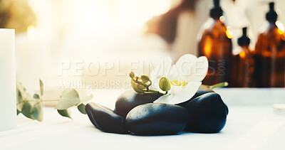 Buy stock photo Spa, empty and flowers with hot stones for aromatherapy, beauty treatment and wellness at resort. Hospitality, background and heat therapy for stress relief, holistic healing and pamper for massage