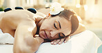 Spa, relax and woman with hot stones for massage, stress relief and holistic treatment for healing. Hospitality, eyes closed and person with heat therapy for pamper, self care and calm for wellness