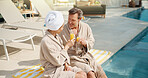Drinks, couple and toast at swimming pool on summer vacation, laugh and smile for conversation. Poolside, mature man and woman cheers with mimosa, anniversary holiday and love celebration outdoor