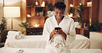 Woman, texting and smile with phone in spa, internet search and typing message on social media app. Resort, guest and happy black person with mobile, reading and communication with contact on website